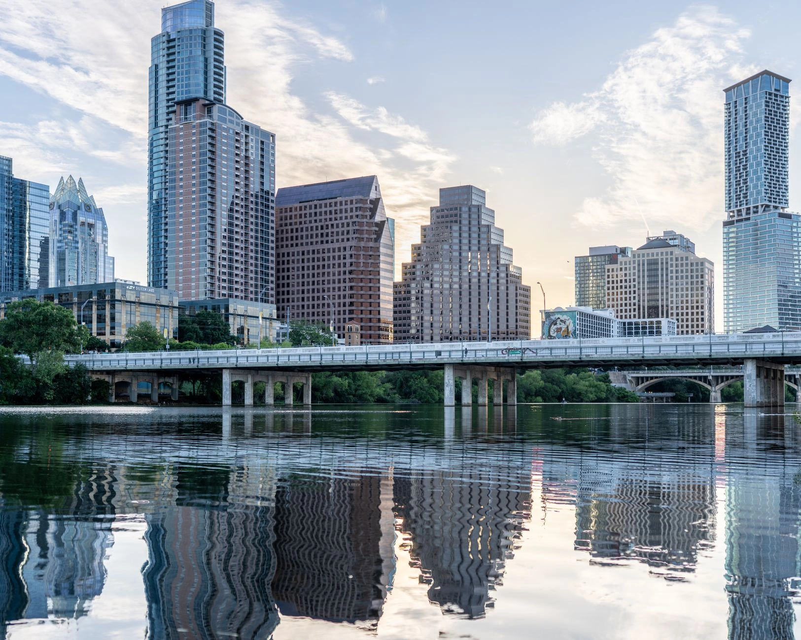 Beautiful view of Austin's skyline with reflections in Lady Bird Lake during daytime.