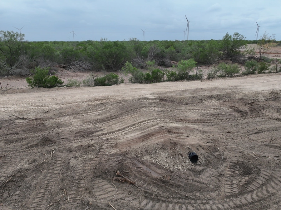 A remote, rugged landscape dotted with wind turbines, showcasing the challenging terrain that A.M. Pitts Construction specializes in for their land improvement, site work, and excavation services.
