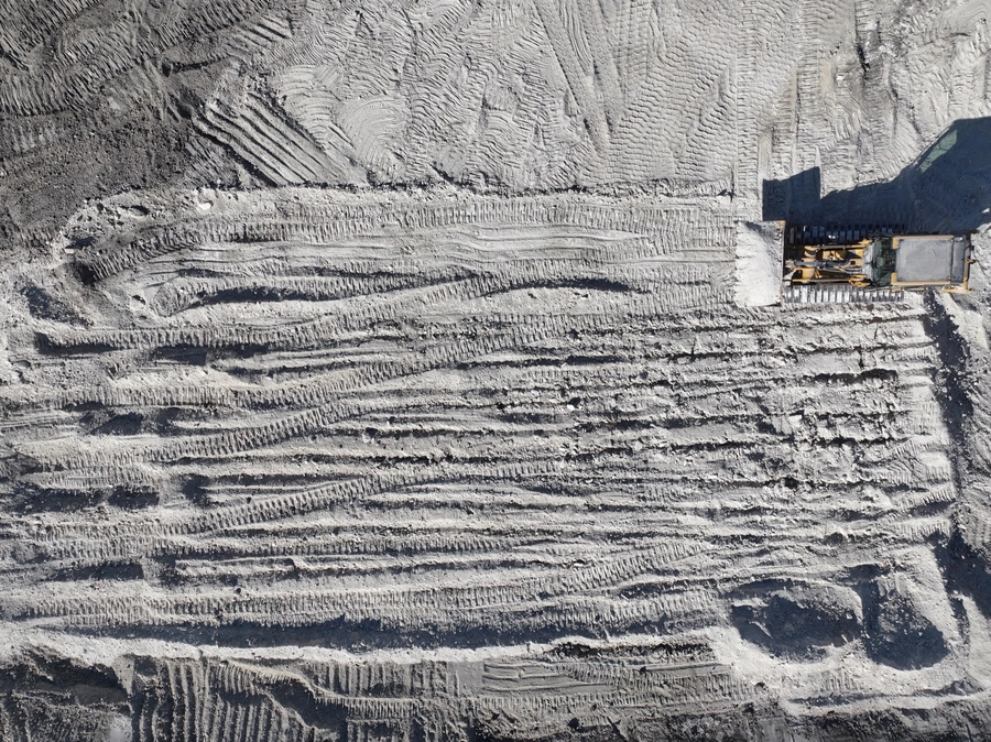 Aerial view of a construction site showing a large excavated area with intricate patterns in the soil, indicating the precision and expertise of the land improvement and excavation work being performed.