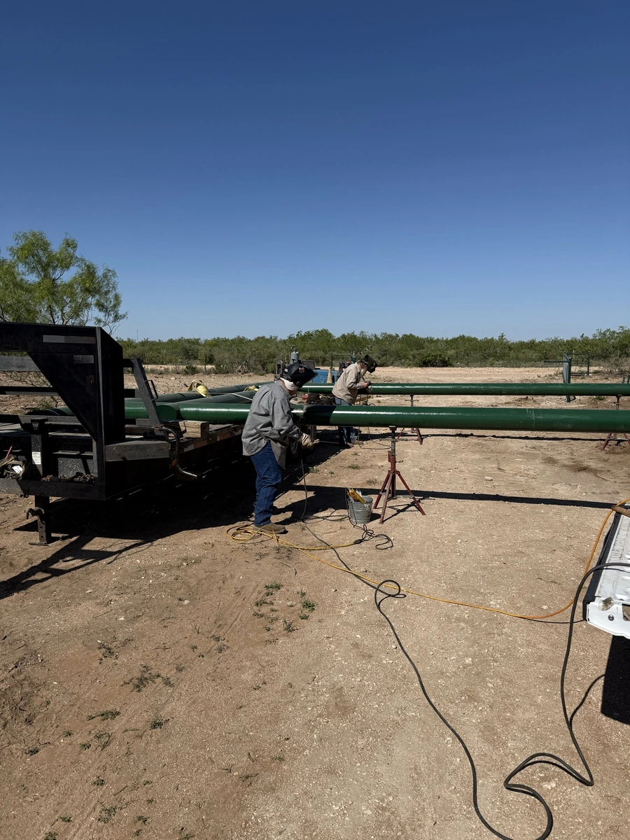 A crew of workers performing land improvement and site work on a rural construction site, with various tools and equipment visible in the foreground.