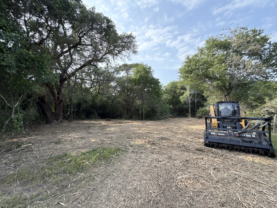 An empty, wooded lot with a bulldozer visible, ready for land clearing and site preparation work.