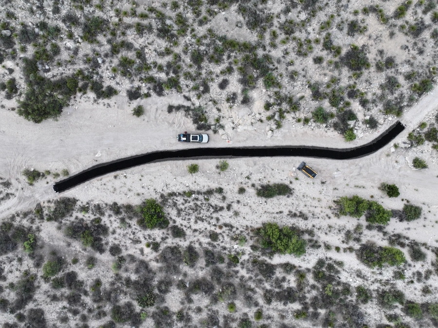 Aerial view of a snowy, winding road cutting through a forested landscape.