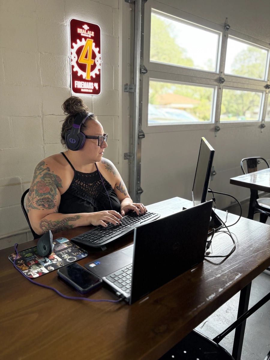 Woman working at computer with a large monitor in Blanco Feed Store&#39;s co-working space. 