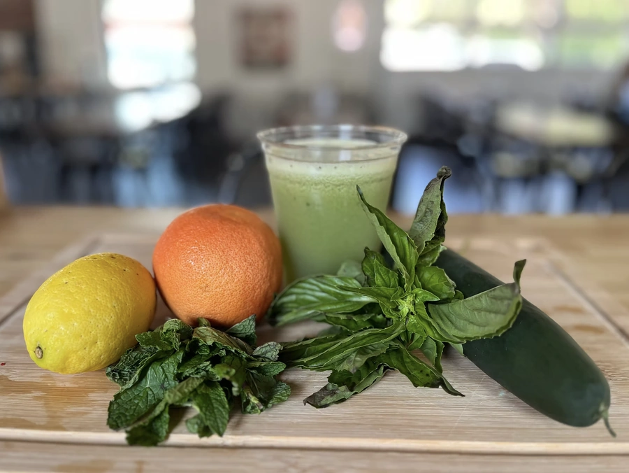 Mr Green fresh juice with an orange, lemon, cucumber and mint leaves