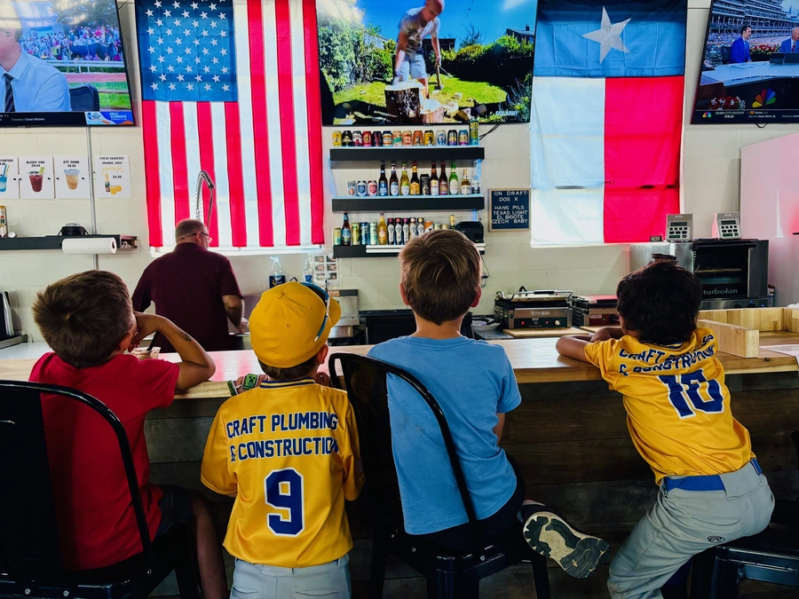 Kids in sports uniforms watching sports on the TVs at the Blanco Feed Store
