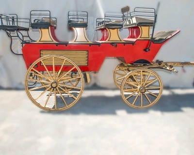 A vintage red stagecoach with wooden wheels and seats, drawn by horses. The stagecoach is parked outdoors against a blurred background.