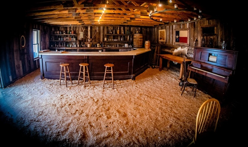 A cozy, rustic bar or pub interior with a long wooden bar, stools, vintage decor, and a warm, inviting atmosphere.