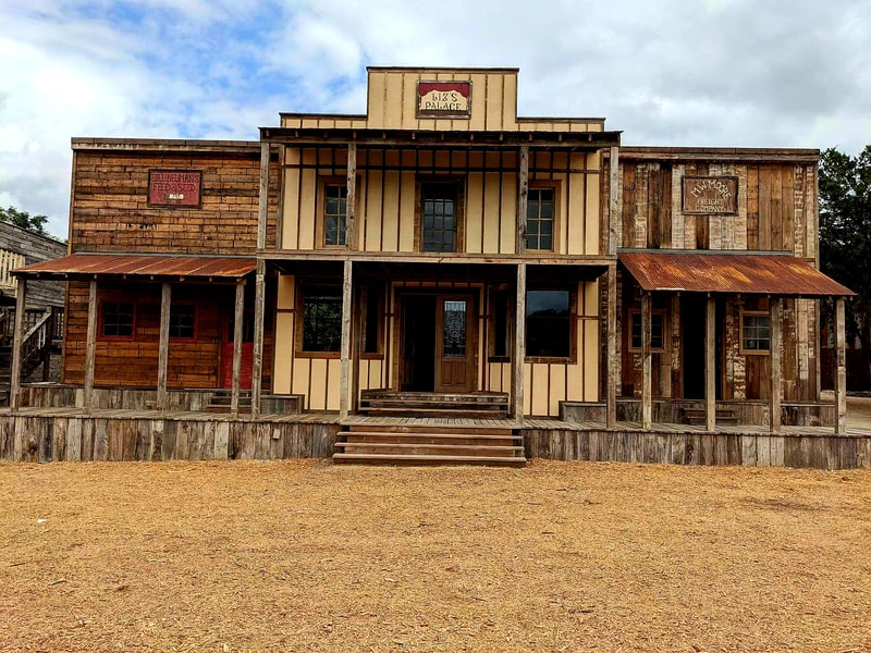 A classic western-style building with a large front porch, wooden siding, and a sign that reads "Saloon".
