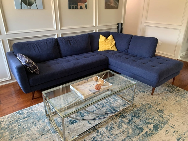 Modern living room with navy blue sectional sofa and glass coffee table