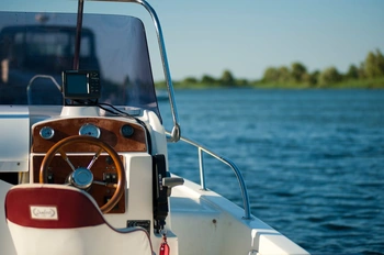 Front seat of a personal boat on a lake with the edge of the lake out of focus in the background