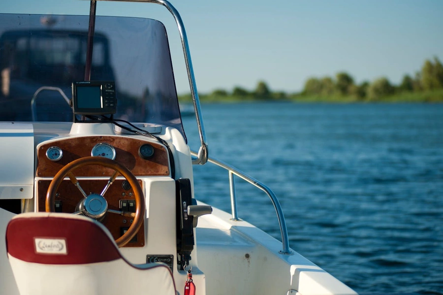 Front seat of a personal boat on a lake with the edge of the lake out of focus in the background