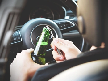 Man opening a beer in a drivers seat