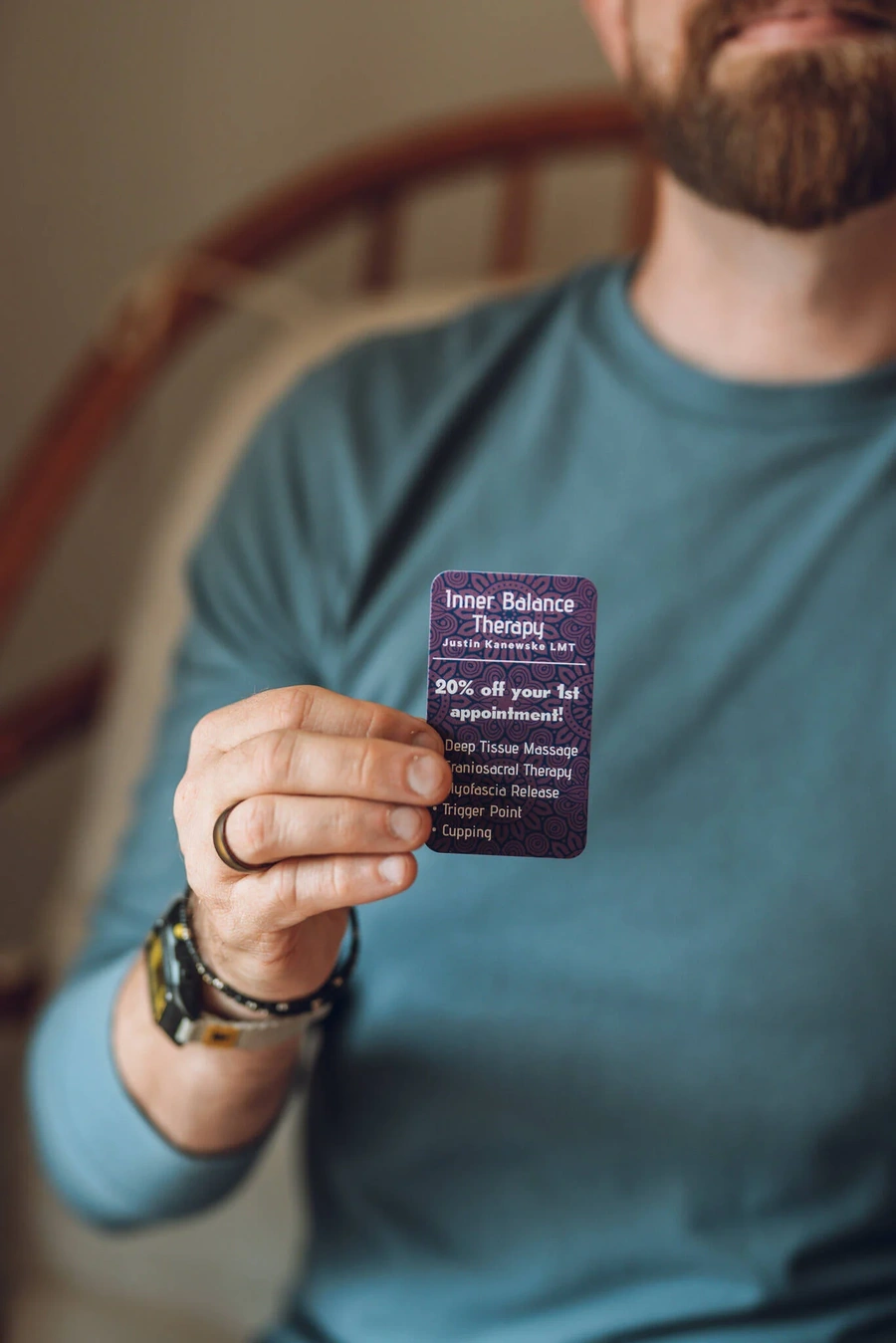 A person holding a business card for Inner Balance Therapy ATX, a massage therapy business.