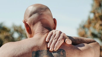 Man massaging his upper back like it's aching 