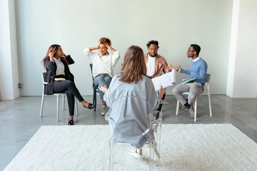 Diverse group of people seated in circular arrangement during therapy session