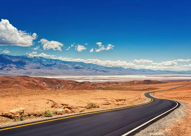 Winding desert road leading into the distance with mountains