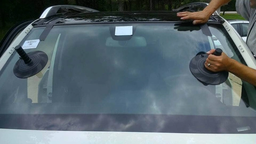 Technician performing final replacement of a new car windshield