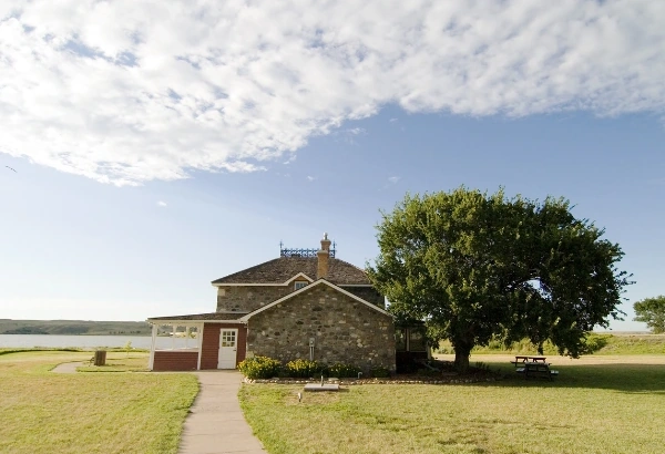 Stone cottage by a lakeside field with a tree and walkway - rural property scene for adverse possession cases