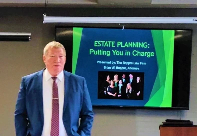 Attorney presenting an estate planning seminar beside a slide titled 'ESTATE PLANNING: Putting You in Charge'