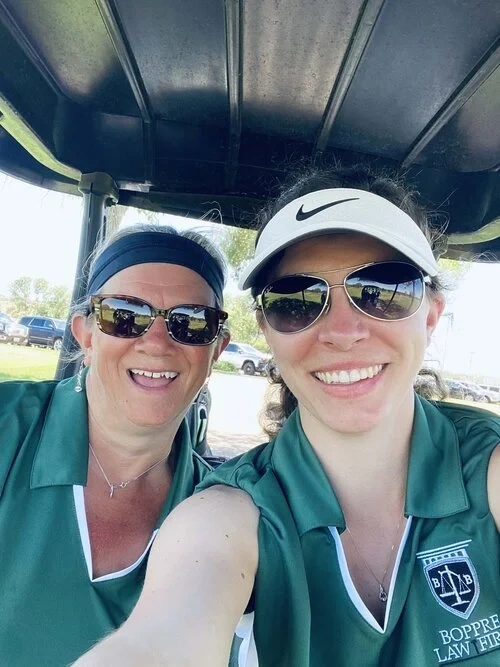 Two volunteers in green polos taking a selfie under a metal parking canopy