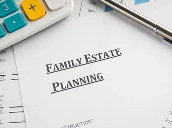 Family estate planning documents on a desk with pen, calculator, and charts