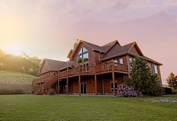 Two-story house with large elevated deck and lawn at sunset, illustrating residential property.