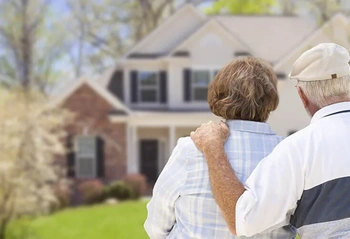 Elderly couple embracing in a front yard facing a suburban home, conveying estate and probate care.