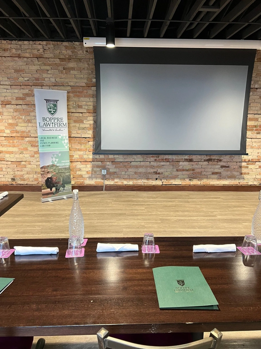 Conference room set for a legal seminar with projection screen, firm banner, and table place settings with a branded folder.