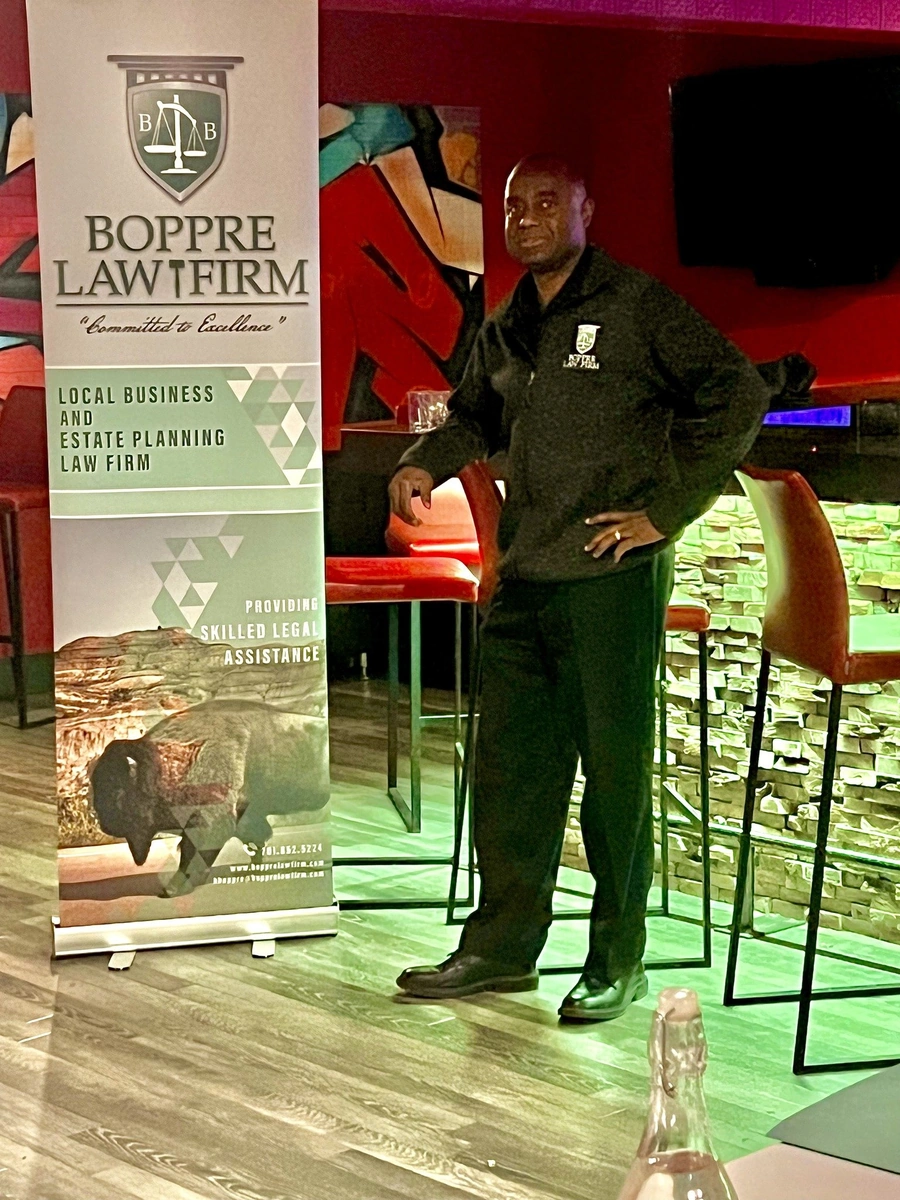 Attorney standing beside a law firm banner at a community outreach event in a lounge