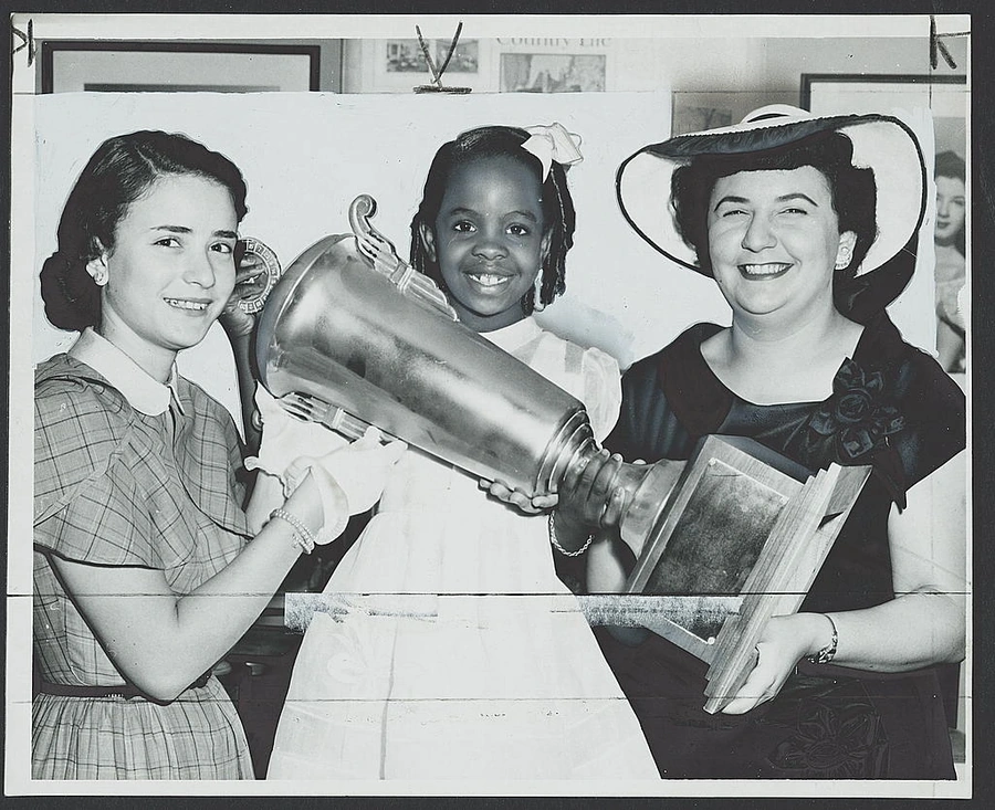 Three people smiling together while presenting a community award.