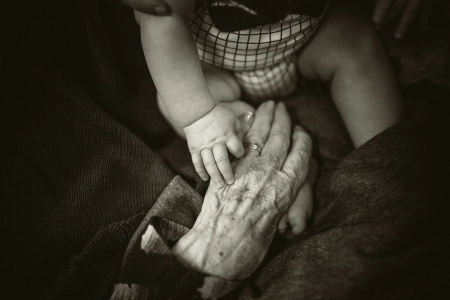 A baby hand on top of a hand of an elderly person