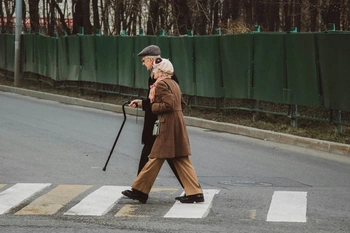 An elderly couple walking across a crosswalk