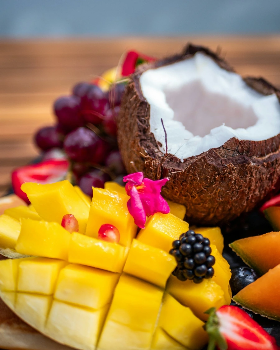 Cut up coconut and mango with strawberries blackberris and flowers