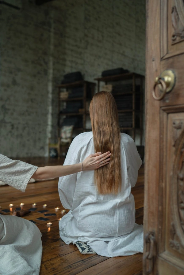 A serene indoor spiritual ritual with two women, candles, and sacred ambiance.