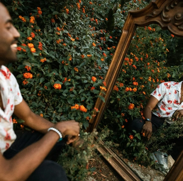 Man looking in mirror with flowers around him