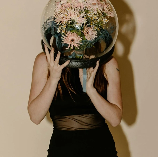 Woman holding an orb with flowers inside in front of her face