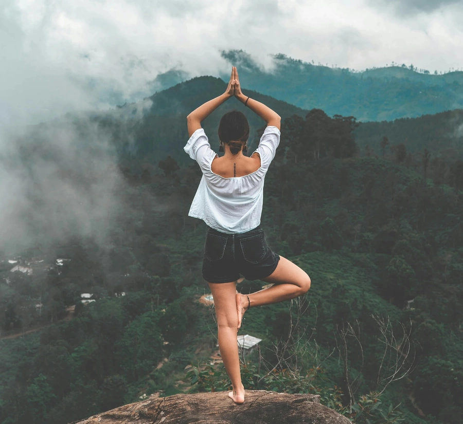 Woman doing a yoga pose on the top of a mountain