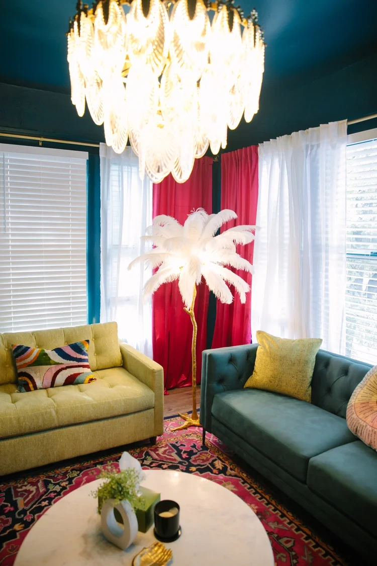 Pink therapy room with green and yellow couch, large chandelier and palm tree light