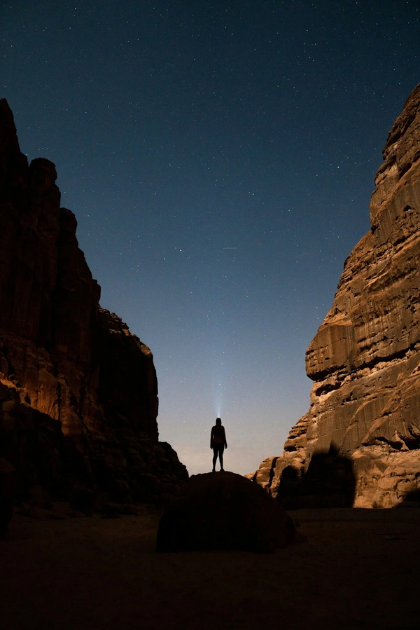 Person looking to starry night time sky between two large cliffs