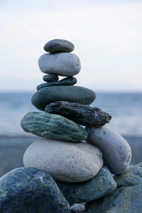 Rocks stacked unevenly and high on a beach with ocean in the background