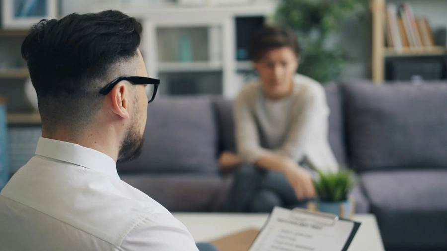 Therapist with clipboard talking to patient