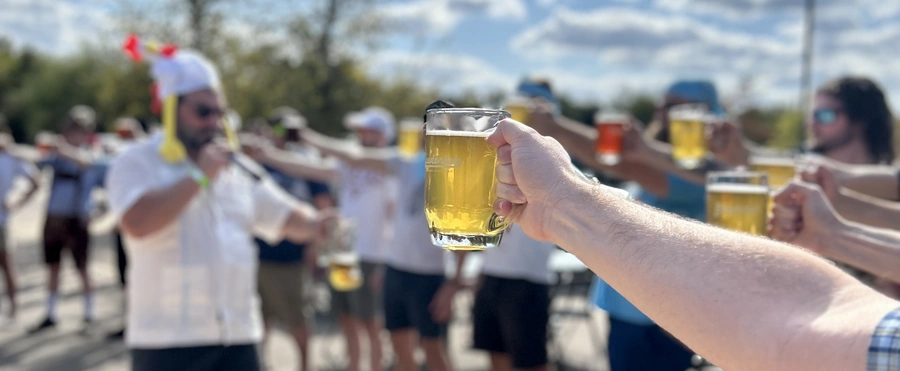 People holding beer steins in a Brewtorberfest competition at The Brewtorium with an MC in the background
