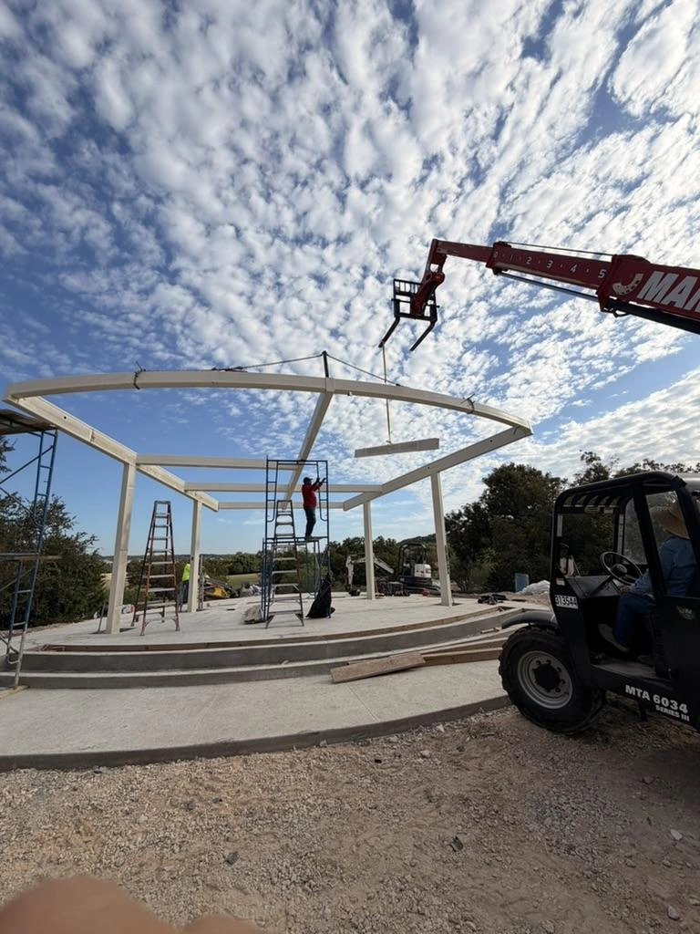 Telehandler lifting a curved steel beam into place on the Garey Park pavilion