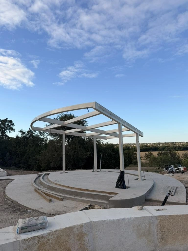 Steel pavilion and canopy framing above the curved concrete stage at Garey Park