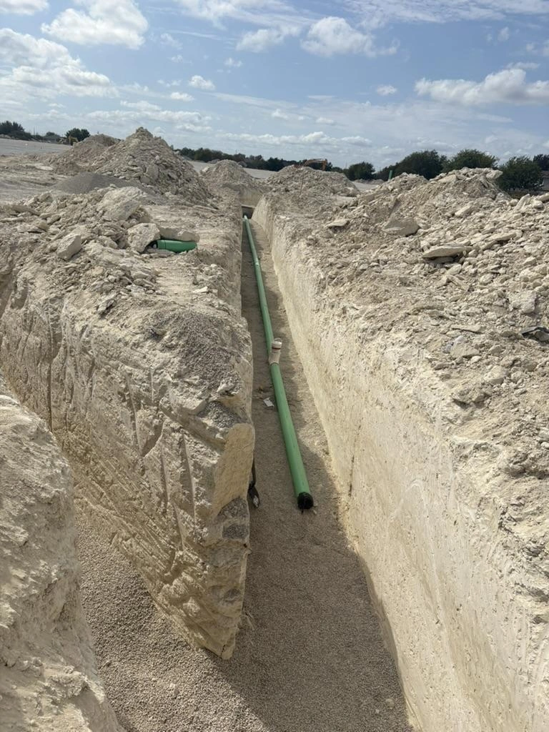 Green PVC utility pipe laid in an open trench at Pflugerville Marketplace