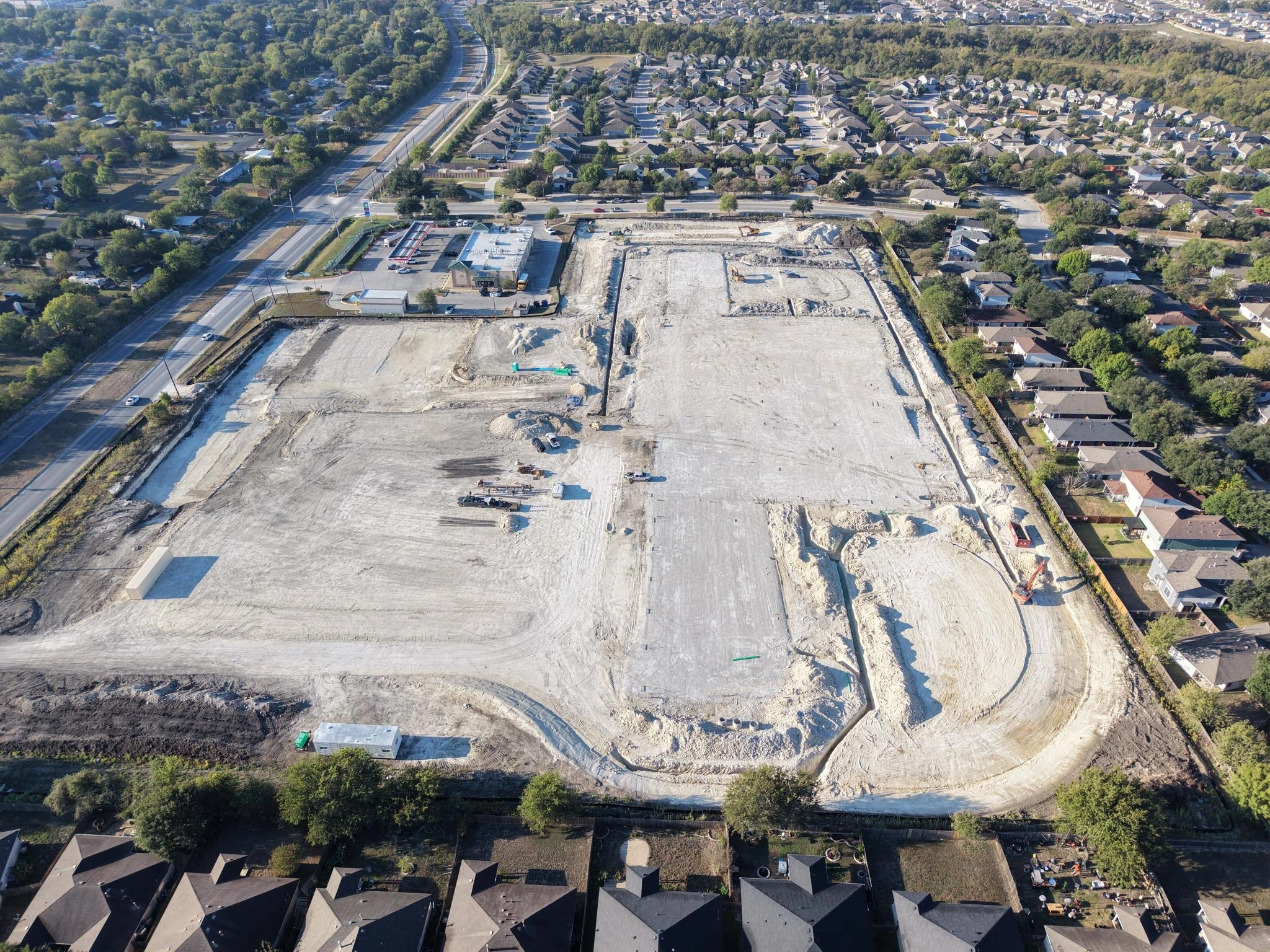 Aerial drone view of the graded Pflugerville Marketplace site with underground utility work underway