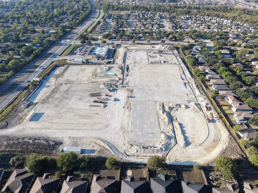 Aerial drone view of the graded Pflugerville Marketplace site with underground utility work underway