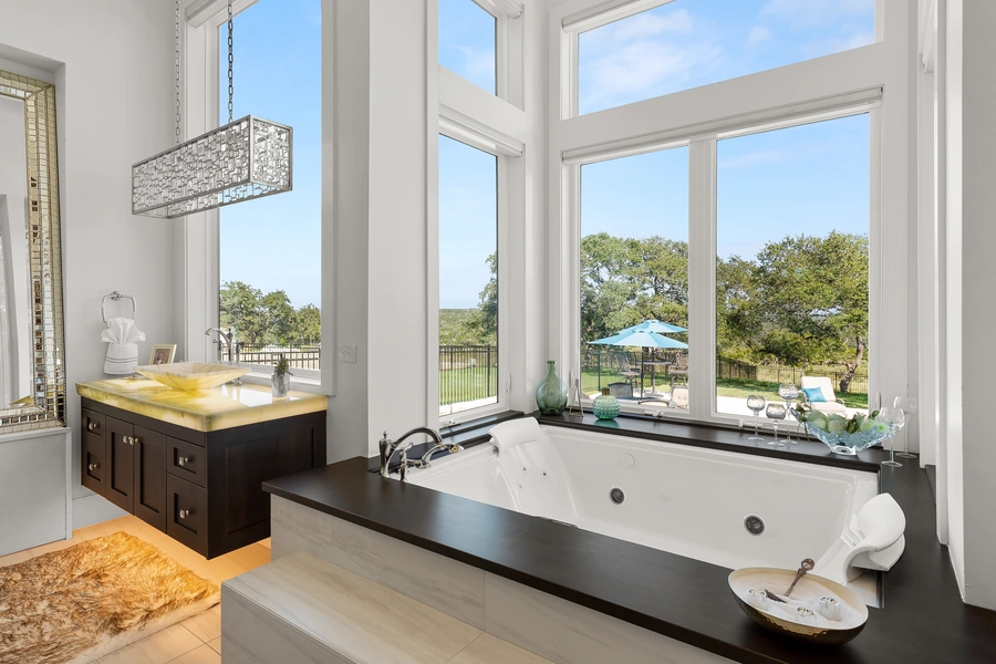 Master bathroom at 1534 Circolare featuring a freestanding tub beside panoramic Hill Country windows with natural light