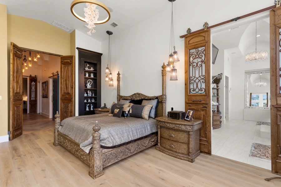 Master bedroom at 1534 Circolare with rustic barn door closet entries, exposed beam ceiling, and warm wood accents