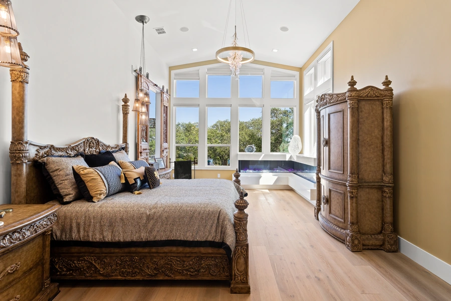 Spacious master bedroom at 1534 Circolare featuring a coffered ceiling, neutral tones, plush seating area, and Hill Country views